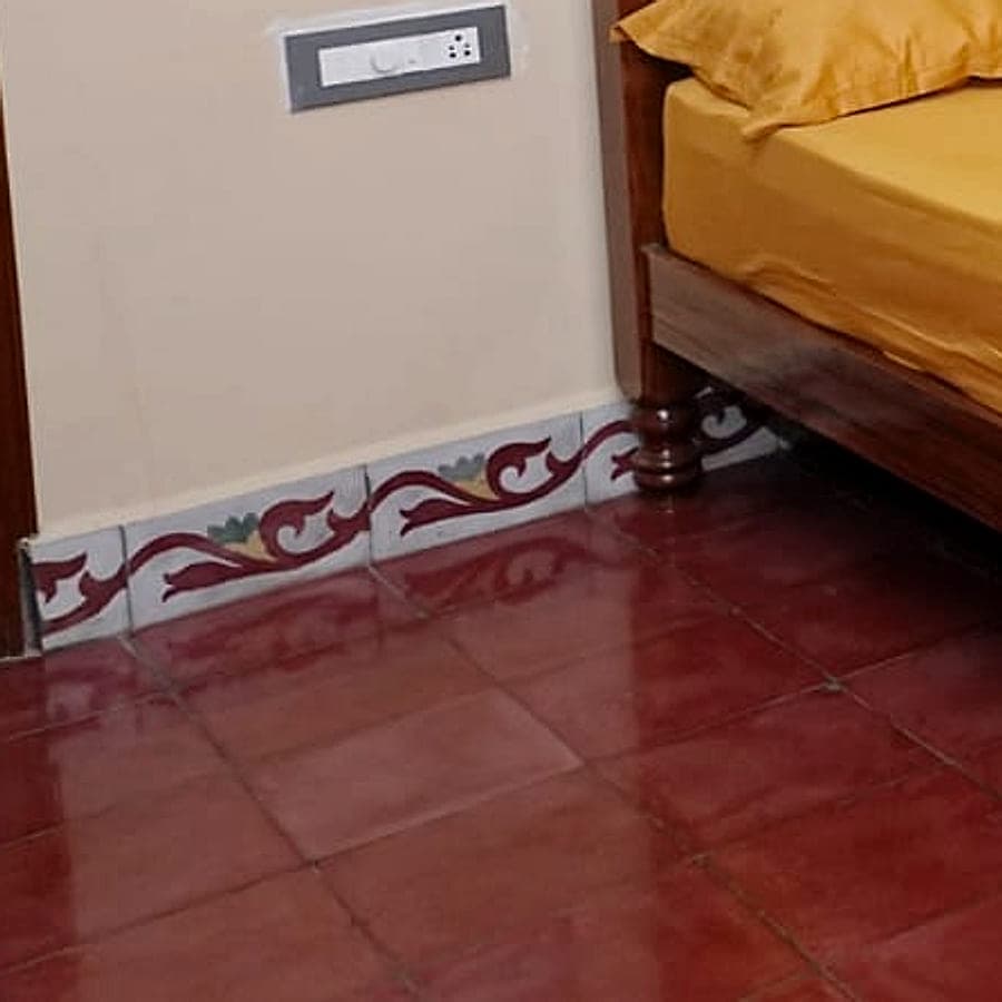 A close view of a painted tile border meeting a polished red oxide floor.