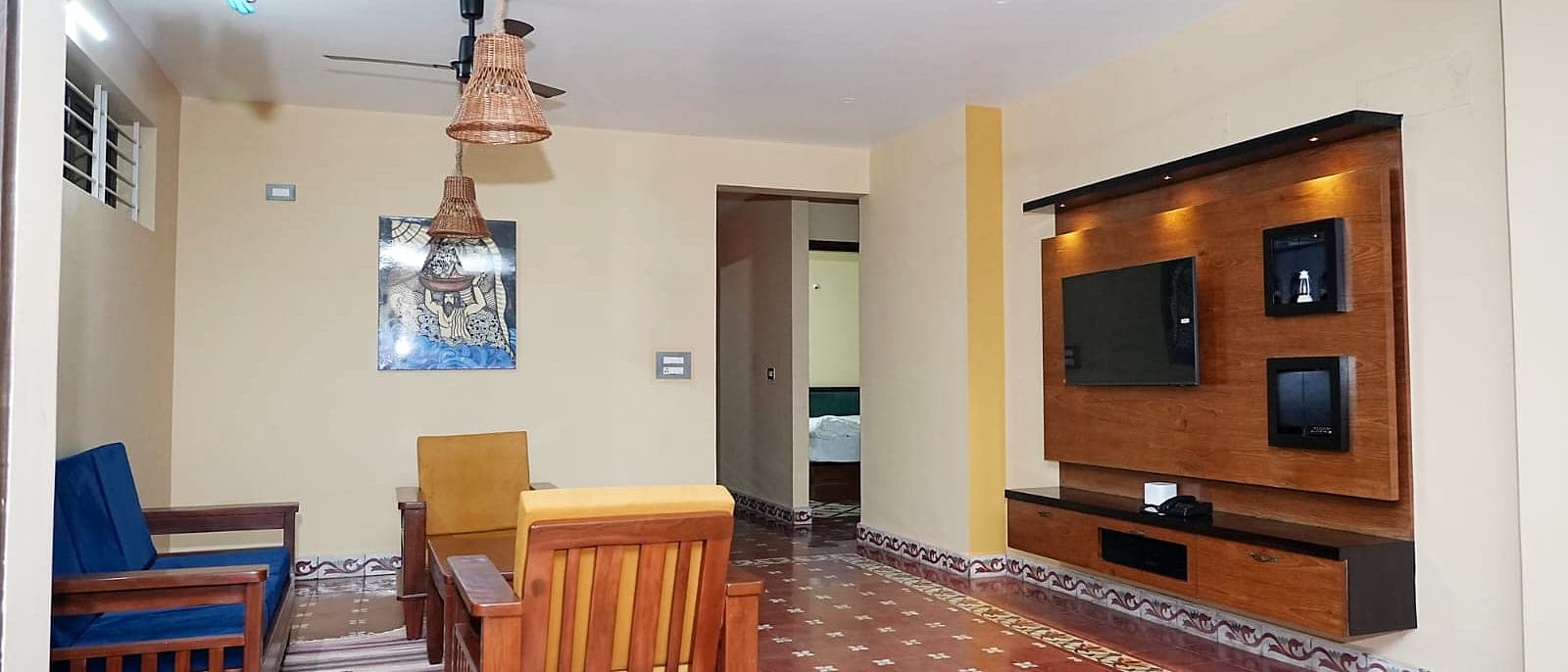 A living room with wooden seating on a deep red tiled floor with a painted border.