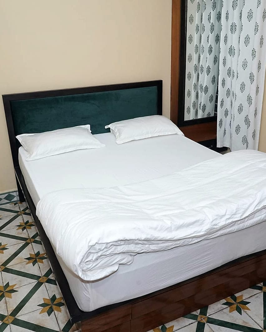 A bedroom standing on handmade floor tiles patterned in ochre, green and chalk white.