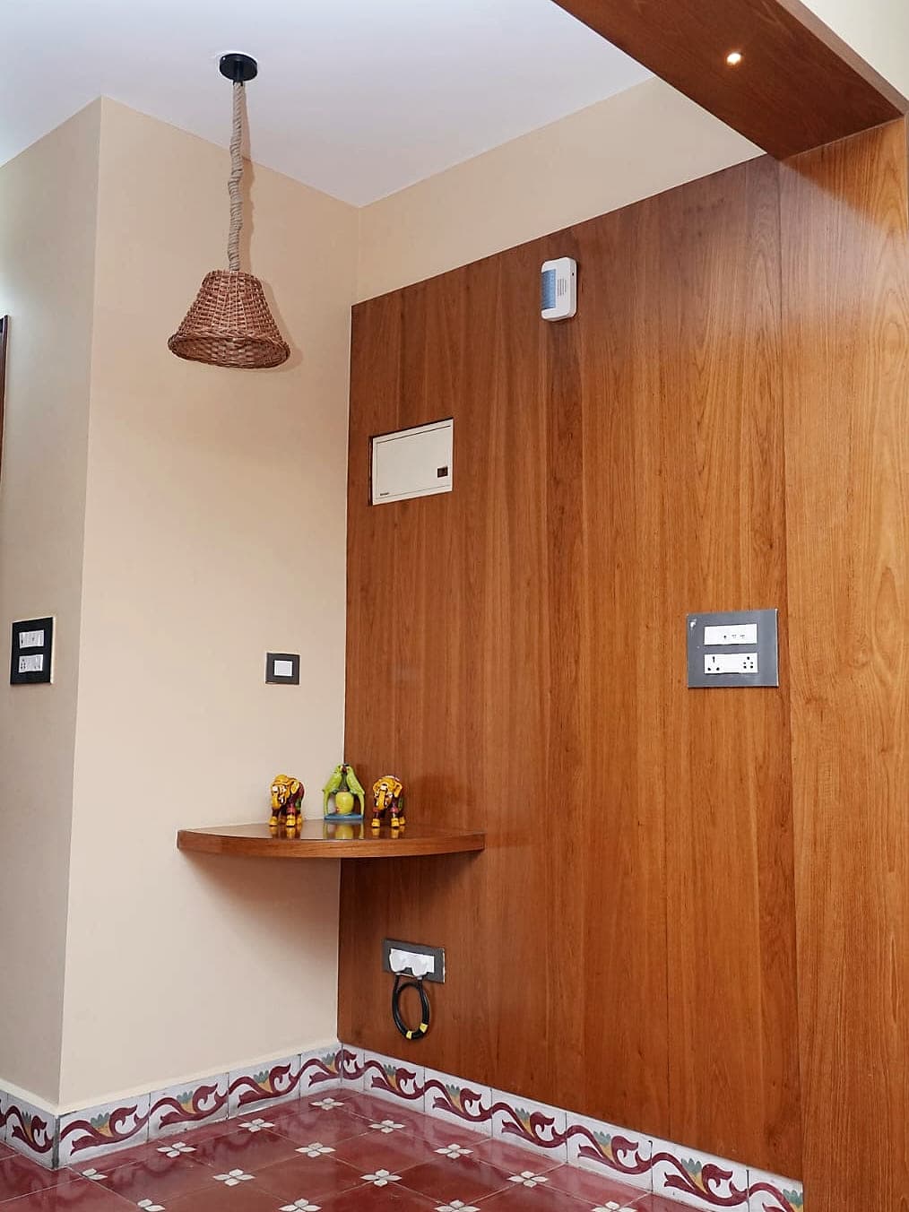 A panelled wooden wall with a small shelf, standing on a tiled floor with a painted border.
