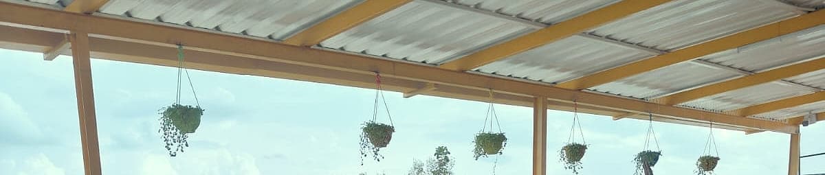 A pergola roof over the terrace, with planters hanging along it against the sky.